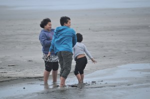 Siblings play at the beach on a windy day in Ōhope, Bay of Plenty, New Zealand.